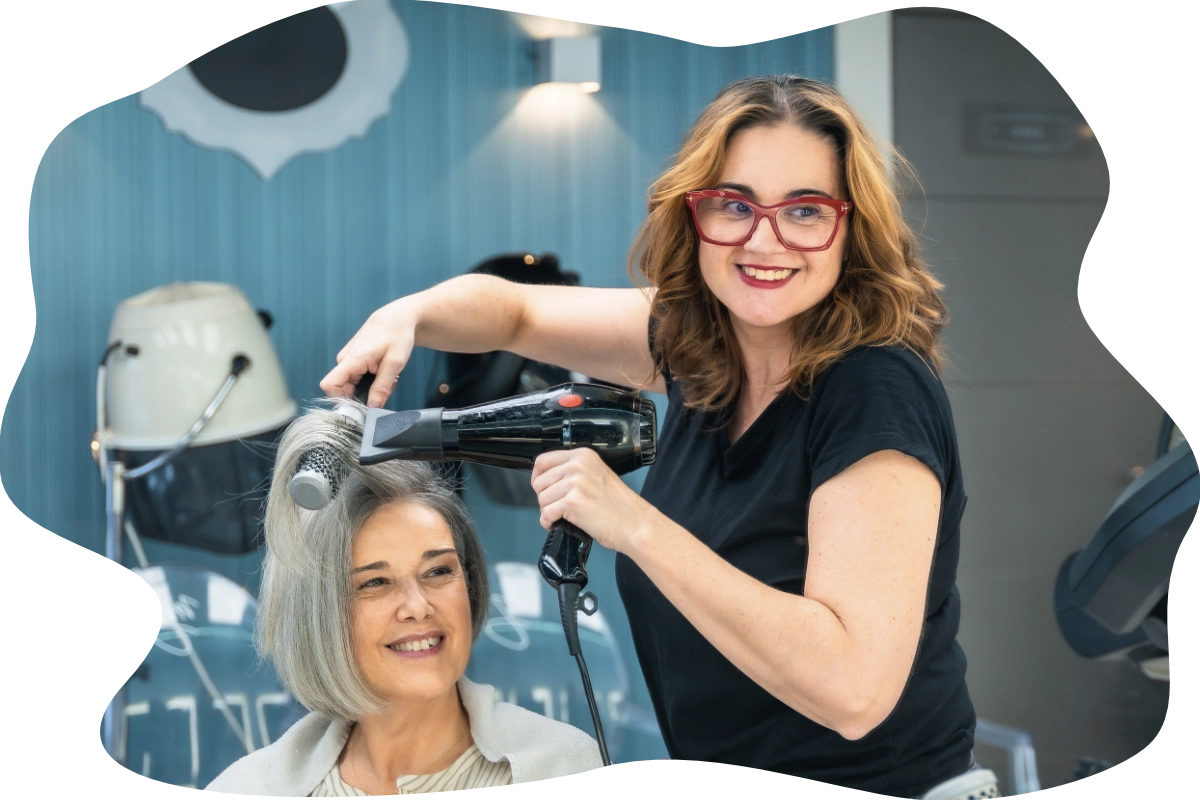 Femme coiffeuse qui coiffe une femme d'âge mûr